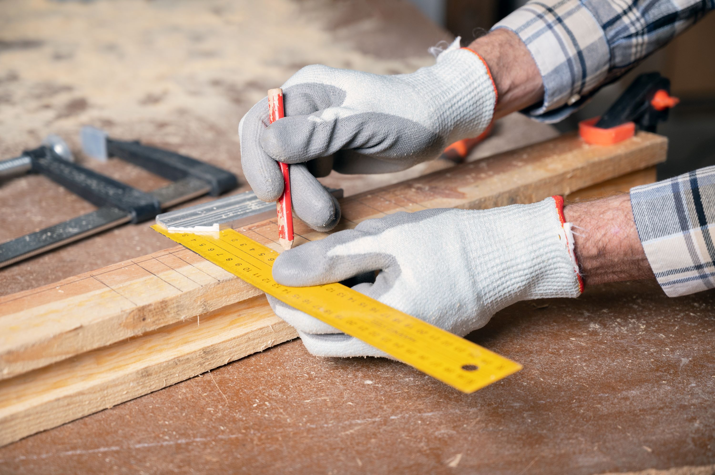 Person zeichnet Markierungen auf ein Holzstück